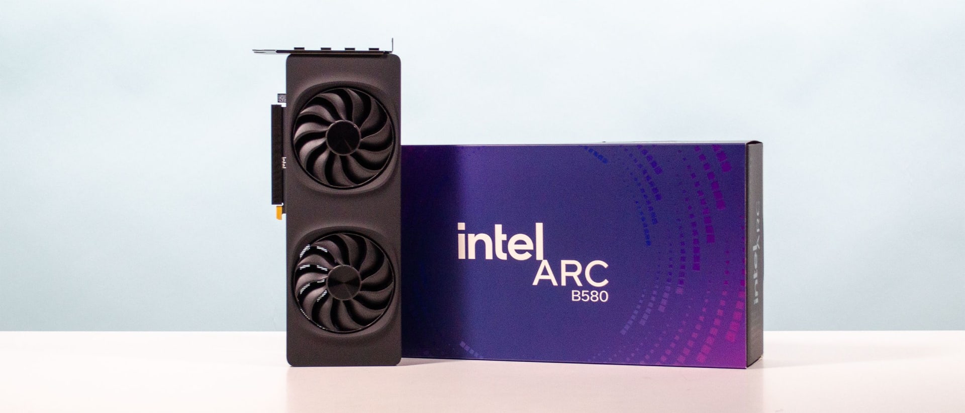 Intel Arc B580 graphics card resting on a desk beside its retail packaging