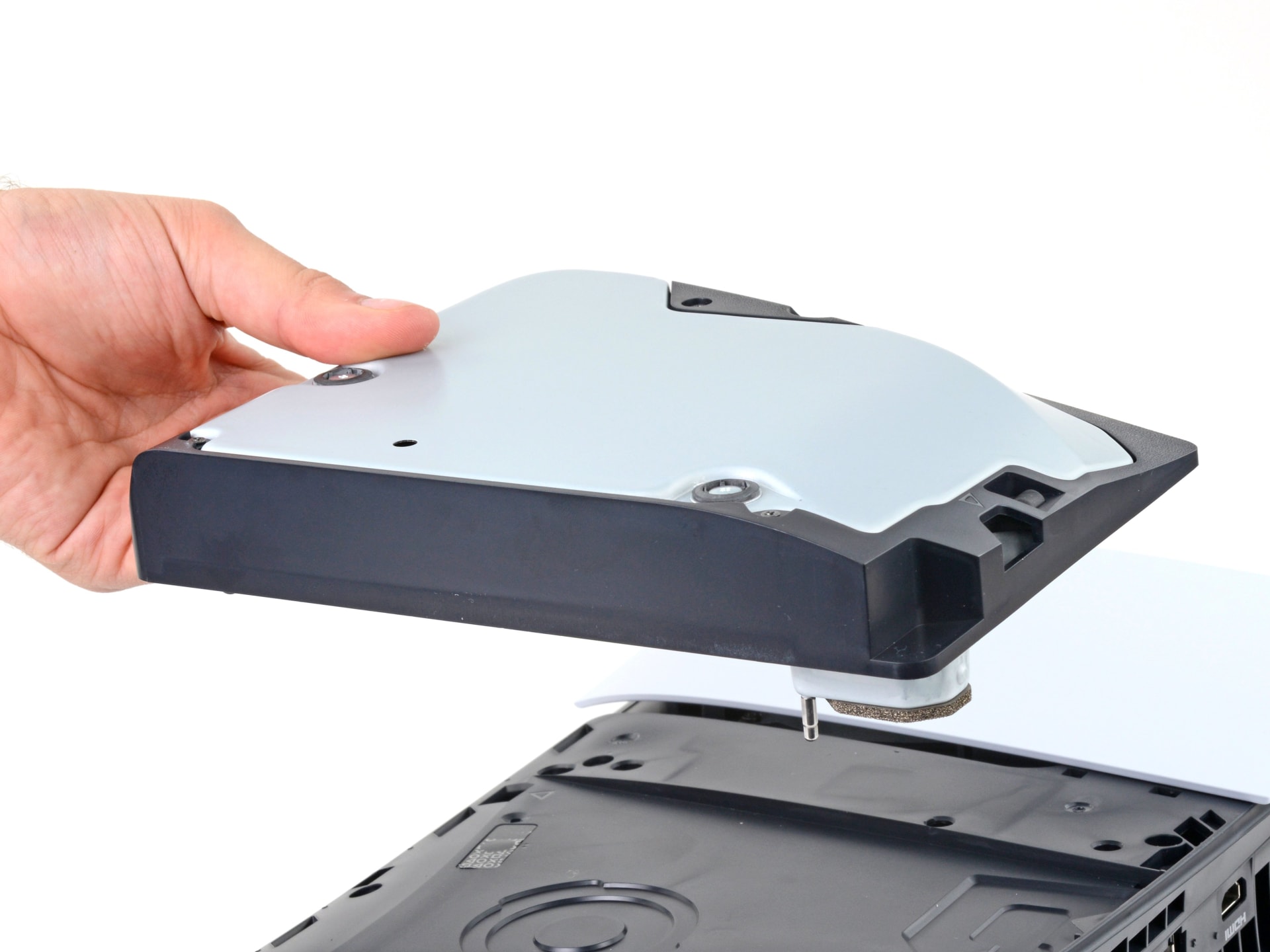 The PS5 disc drive module lifted out of the console showing the internal bracket and housing