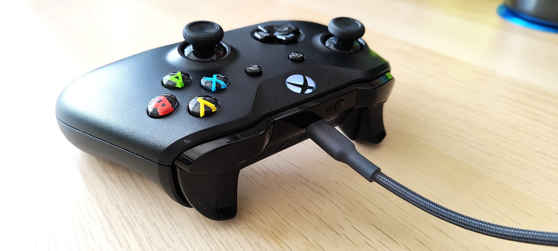 An Xbox controller connected to a console with a USB-C cable for a wired connection