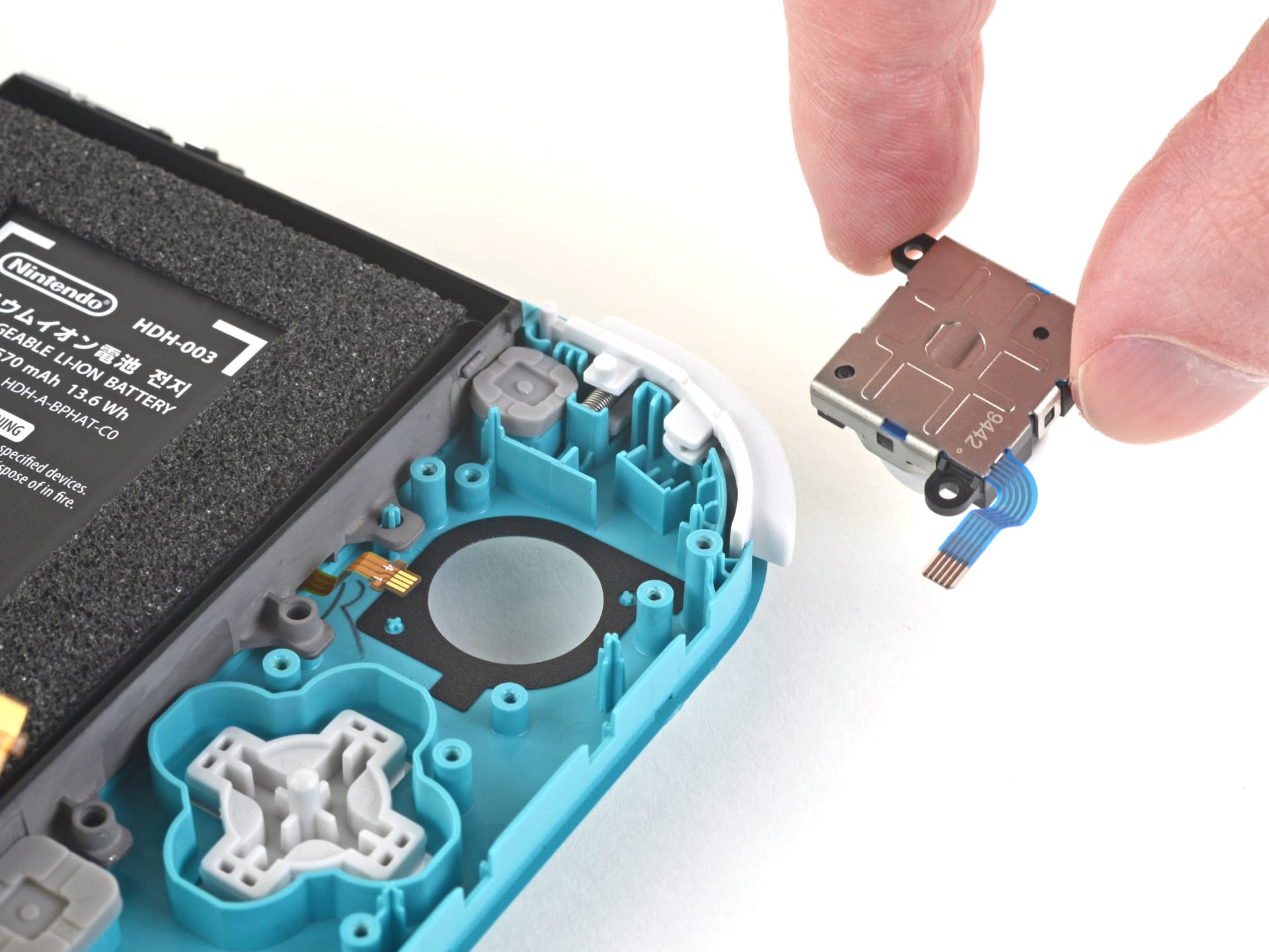 A Joy-Con 2 opened during teardown showing the internal board and thumbstick assembly