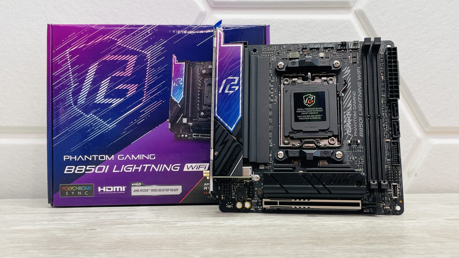 ASRock Phantom Gaming B850I Lightning WiFi mini-ITX motherboard standing in front of its retail box, showing two DDR5 slots beside the AM5 socket