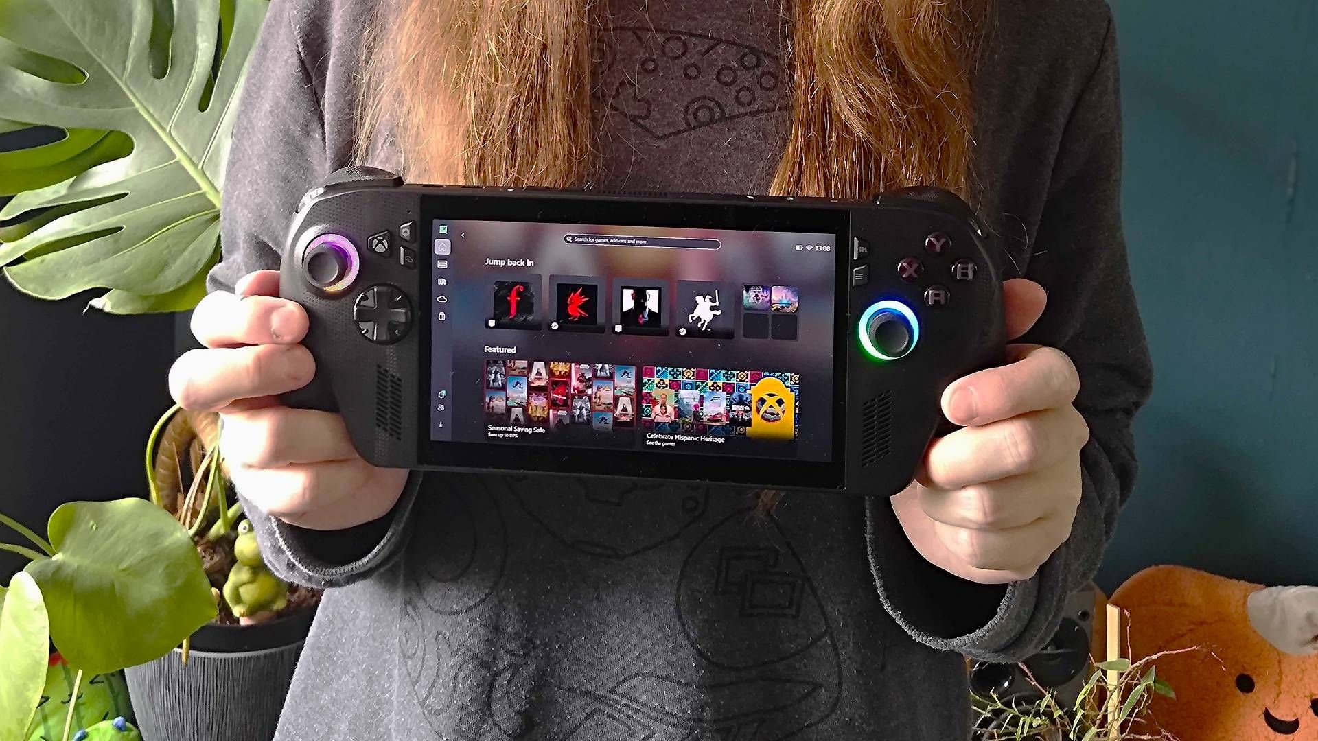 Person holding the ROG Xbox Ally X handheld showing the Xbox full screen experience home screen