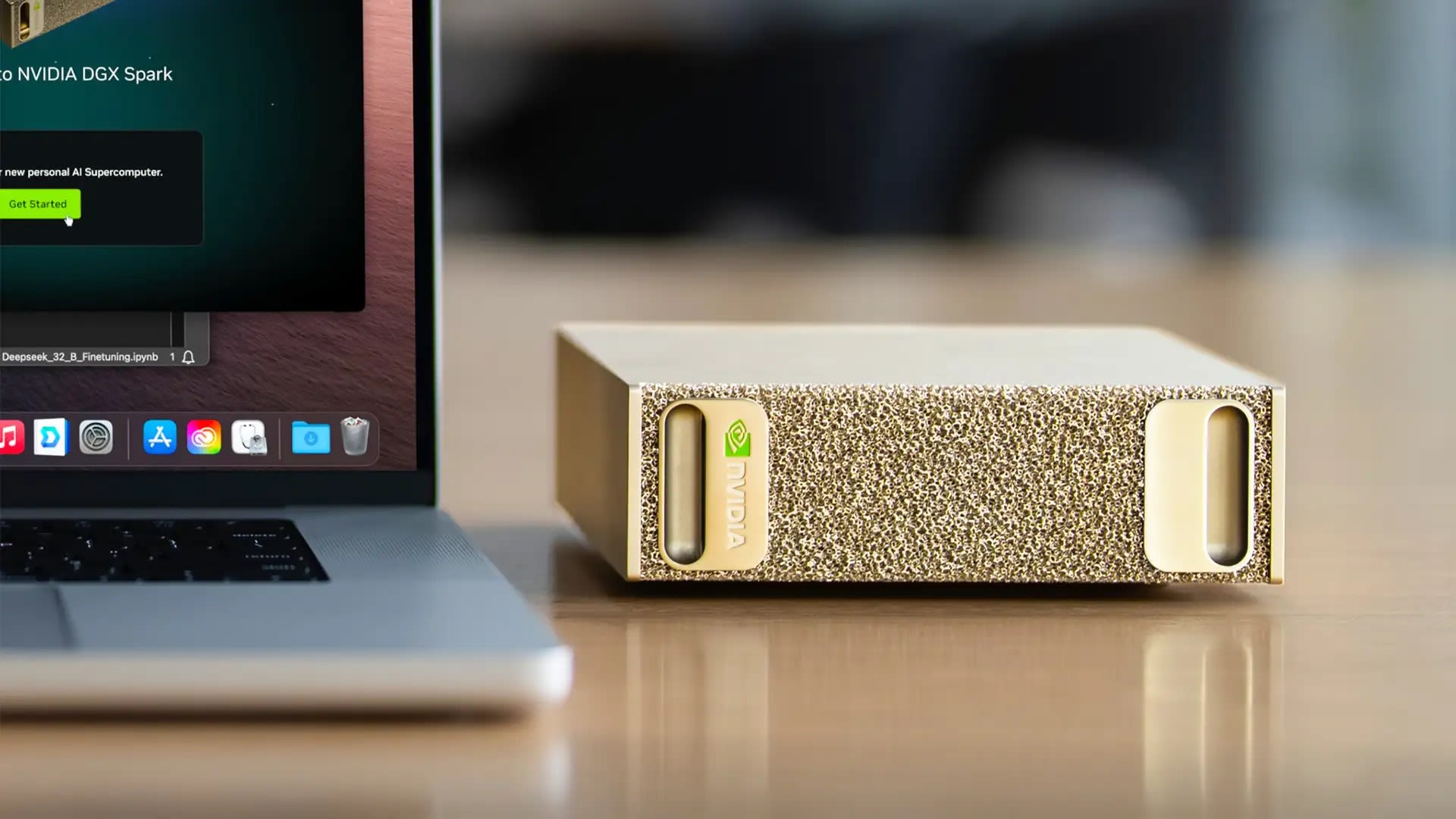 The gold Nvidia DGX Spark mini PC on a wooden desk next to a laptop showing the DGX Spark setup screen
