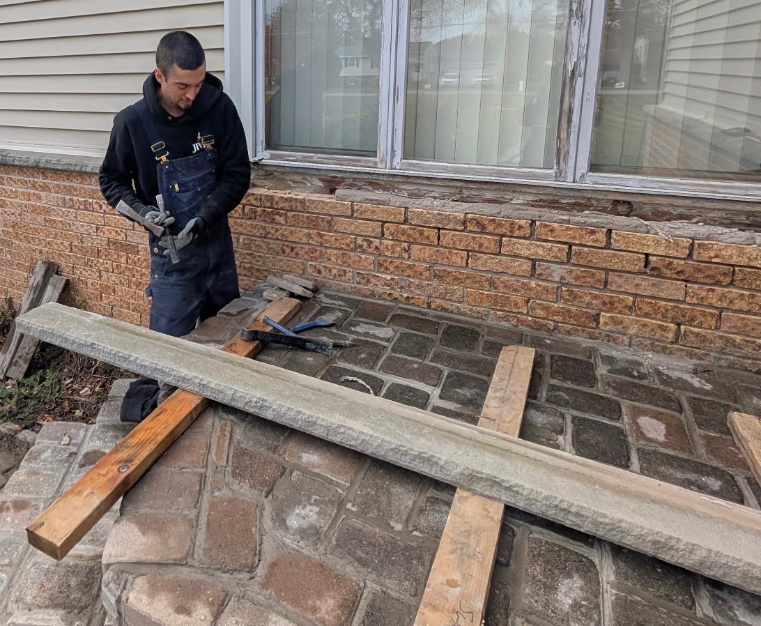 Dan Quinn of Genesee Valley Stone Works hand-setting stone during a patio restoration project