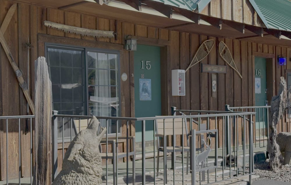 A classic single-story motel exterior where cars can park directly outside private room entrances, demonstrating the Boutel architectural standard
