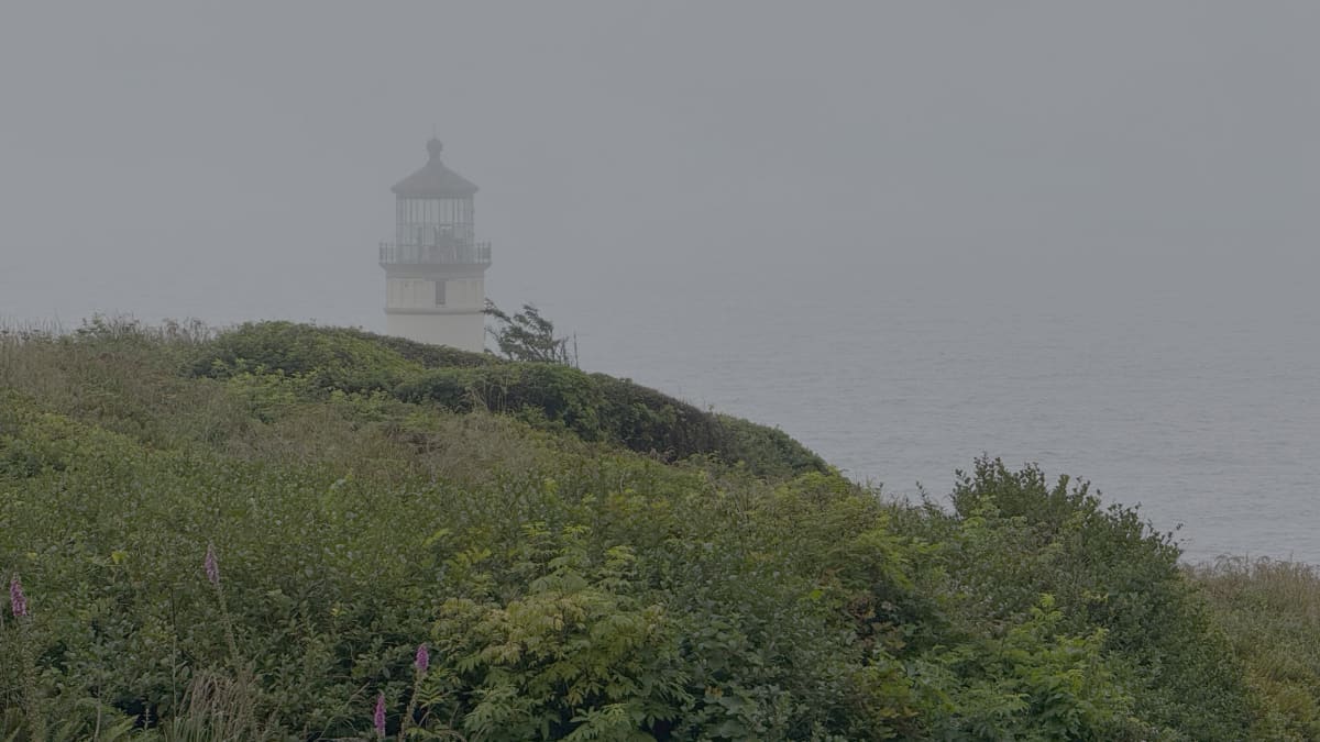 Cape Disappointment Lighthouse, the 1856 tower, standing in coastal fog on its headland above the Columbia River bar