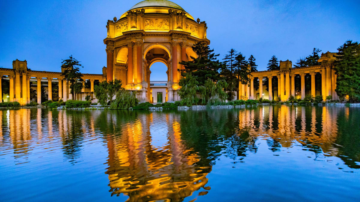 The domed rotunda and colonnade of the Palace of Fine Arts reflected in its lagoon at dusk in San Francisco, California