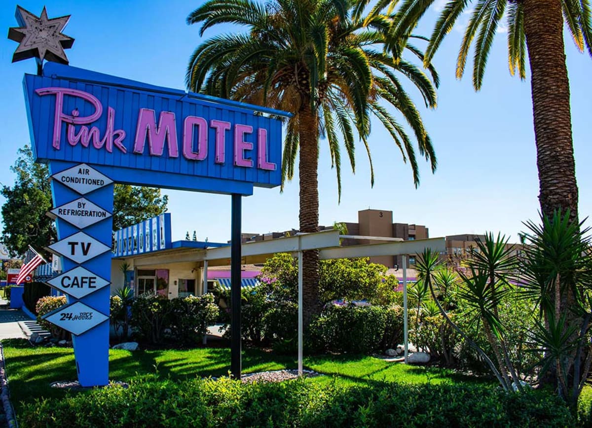 Vintage Pink Motel neon sign with palm trees. Mid-century American roadside motel