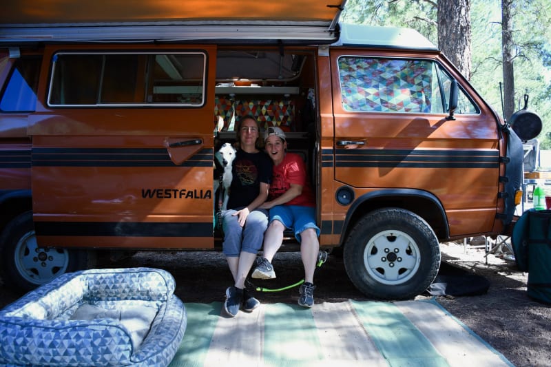 Founder Sarah Powers and family sitting in the doorway of an orange VW Westfalia camper van