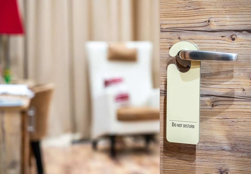 Do Not Disturb sign on a wood-paneled motel door. Private entrance, cozy affordable motel with character