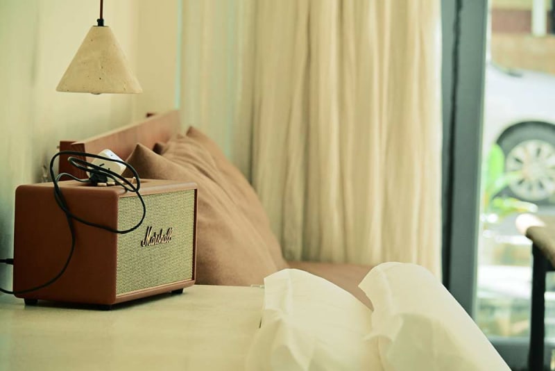 Marshall speaker on a nightstand with car visible through motel window. Vintage affordable inn with drive-up access and character
