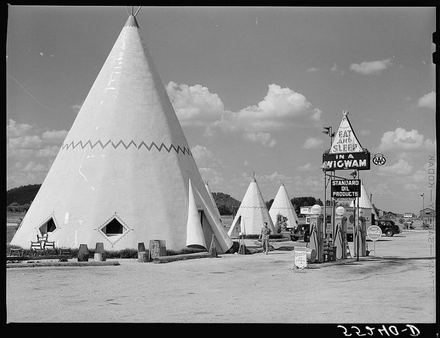 A row of white teepee-shaped roadside tourist cabins with a gas pump beside a highway south of Bardstown, Kentucky in 1940