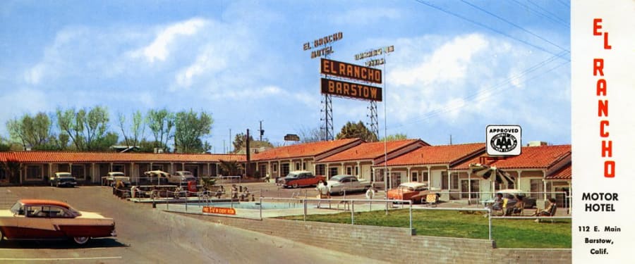 A 1950s color postcard of the El Rancho Motor Hotel on Route 66 in Barstow, California, with its neon sign, red-tile rooms, courtyard pool, and 1950s cars