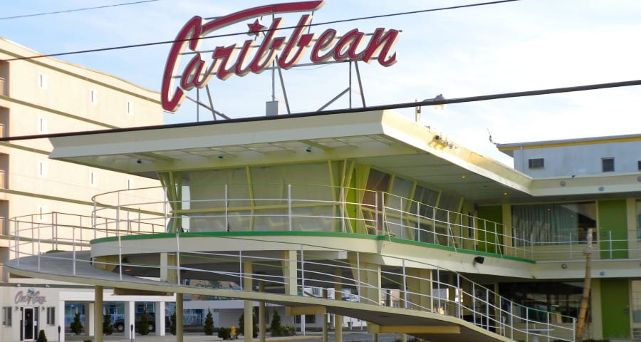The Caribbean Motel in Wildwood, New Jersey, a mid-century Googie motel with a swooping neon script sign, a cantilevered roof, and a curved ramp