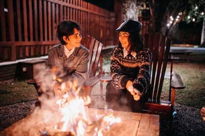 Couple at a firepit outside an inexpensive roadside motel at night, an affordable road trip stay with character