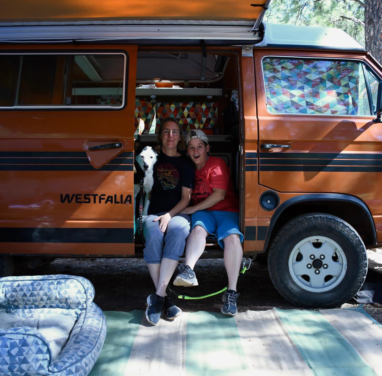 Founder Sarah Powers and family sitting in the doorway of an orange VW Westfalia camper van