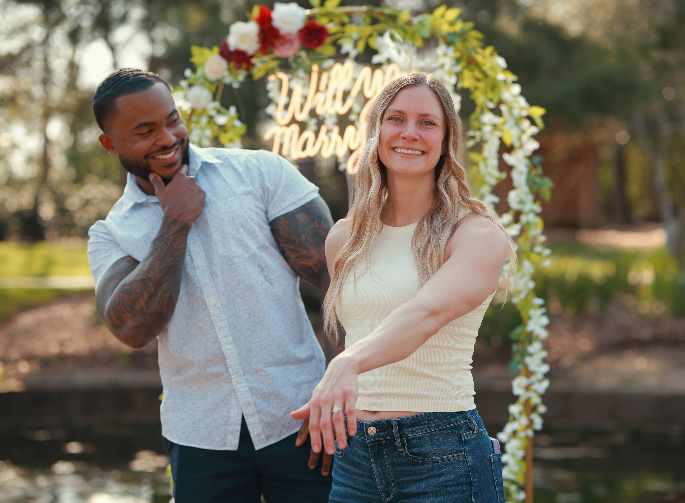 Newly engaged couple showing the ring under a Will You Marry Me sign at Mercer Botanic Gardens