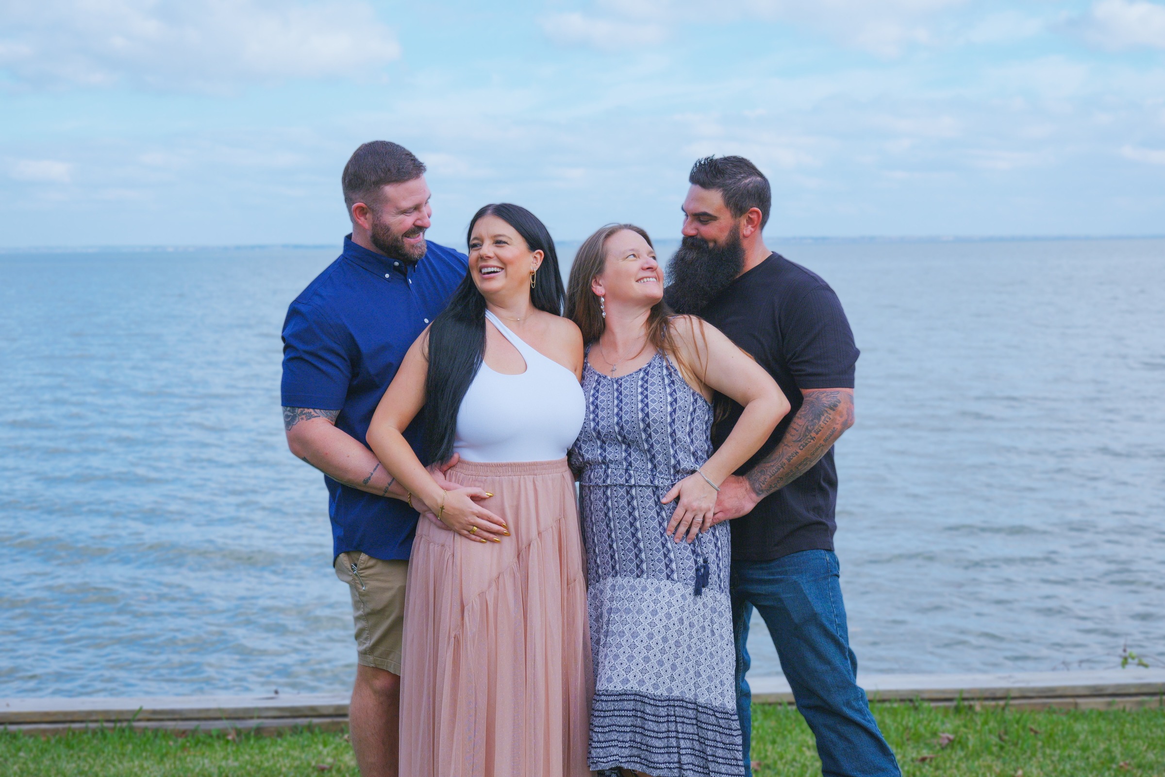 Two couples laughing together on a lakeshore under a blue sky