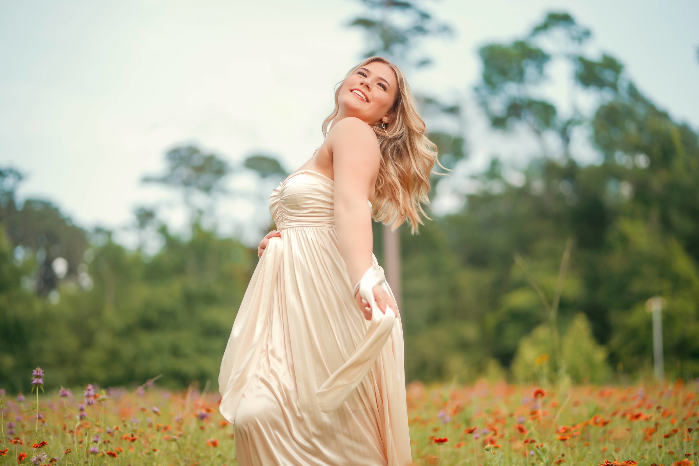 Woman in a flowing gown in a field of orange wildflowers