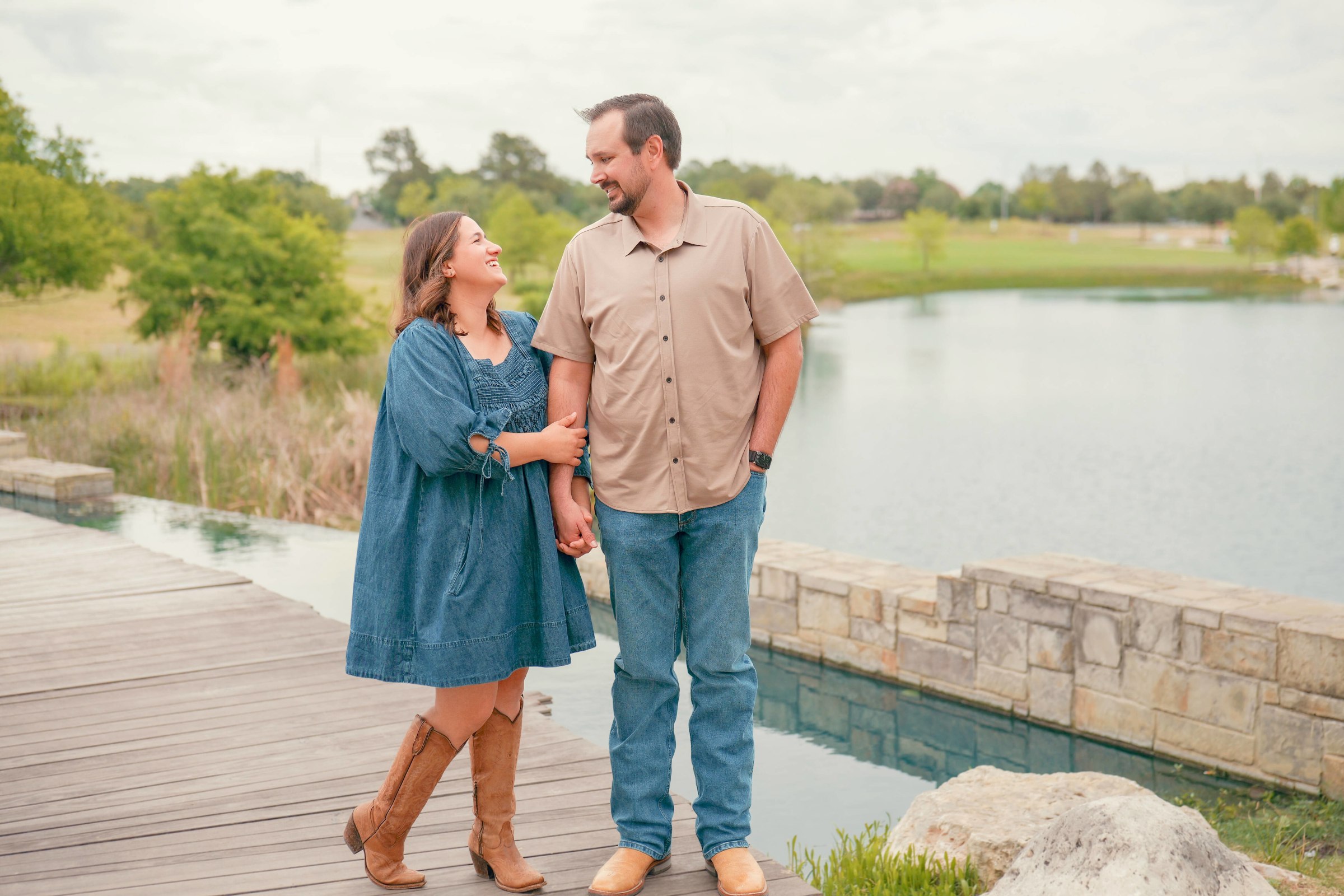 Couple standing arm in arm on a wooden walkway beside a lake