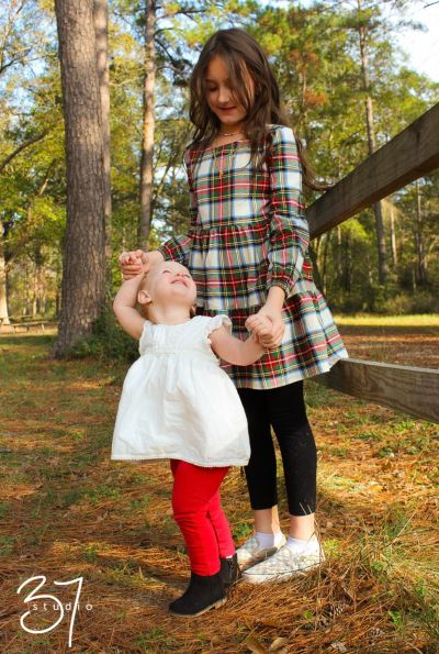 Professional kids portrait of a brother and sister laughing in a sunlit field in Pinehurst, TX.