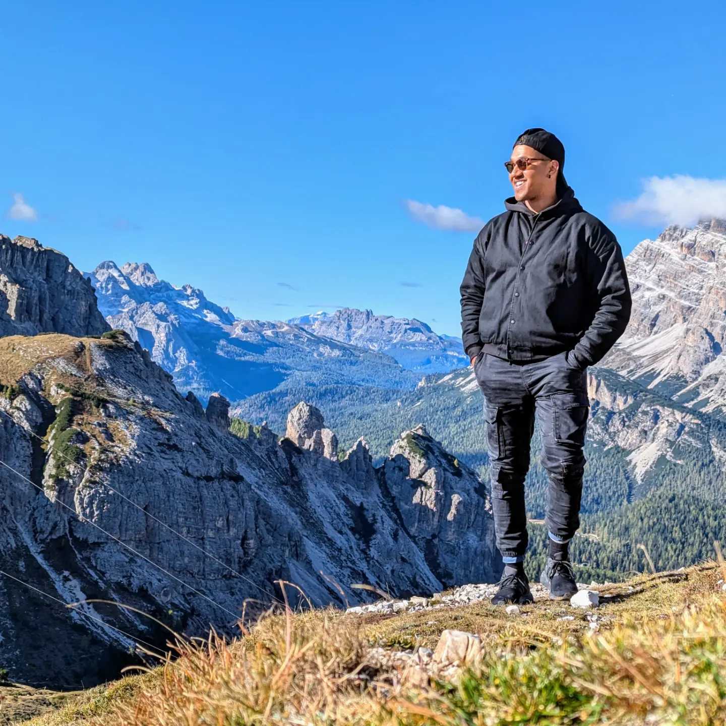 a man standing on a hill staring into the sun