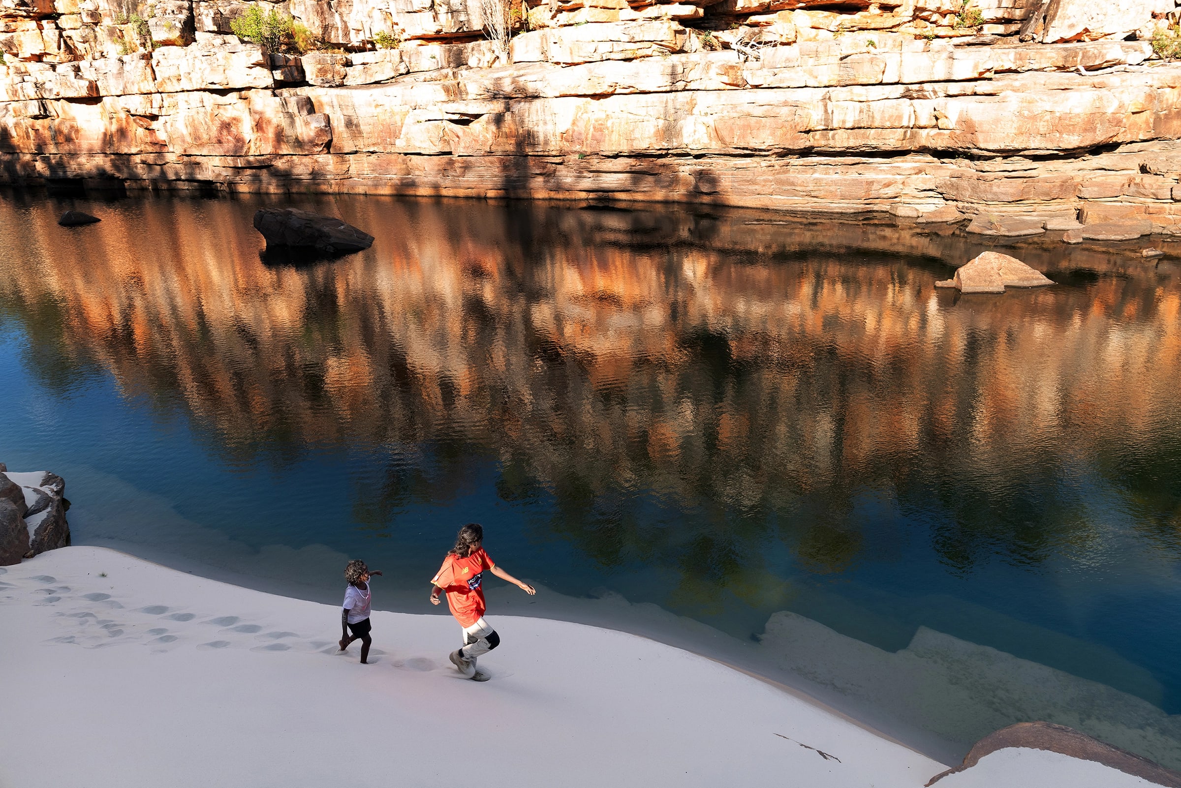 Daluk ranger and wurdyaw (child) walking along a river in the Warddeken IPA