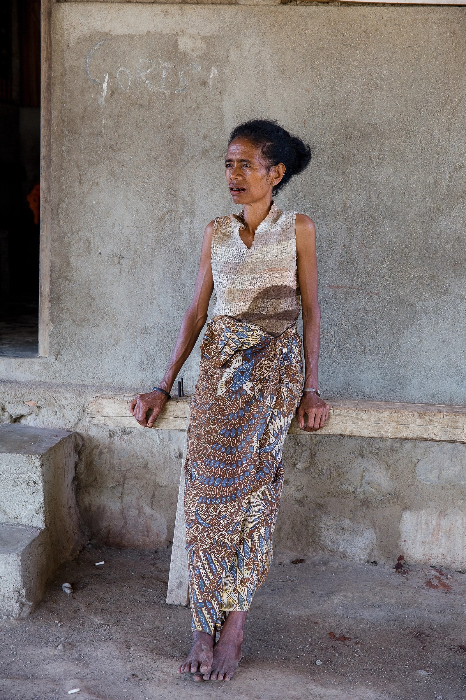 Timorese woman standing next to concrete wall