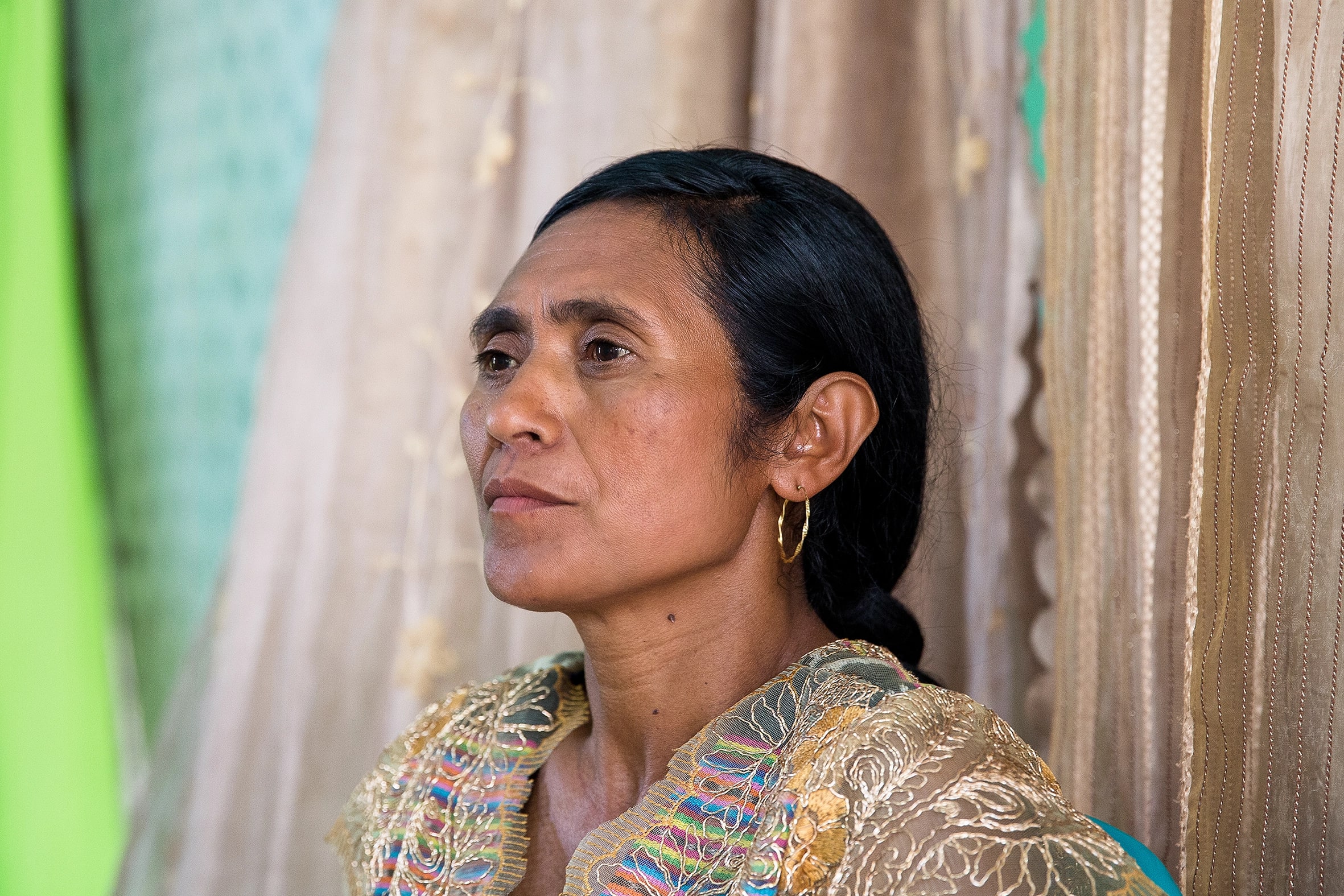 Woman with colourful dress and fabrics in the distance in Timor Leste