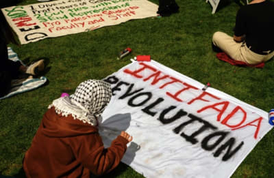 A Pro-Hamas protestors writing 'Intifada Revolution' on a cloth
