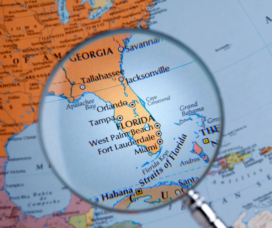 A magnifying glass on top of a map of Miami, FL showing luxury real estate investments.