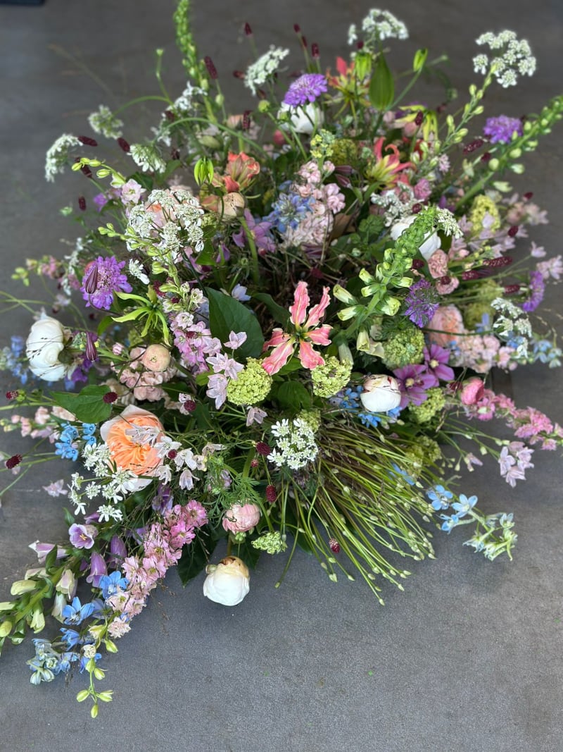 Een wit rouwstuk als kistbedekking, samengesteld door Atelier Bloeiend