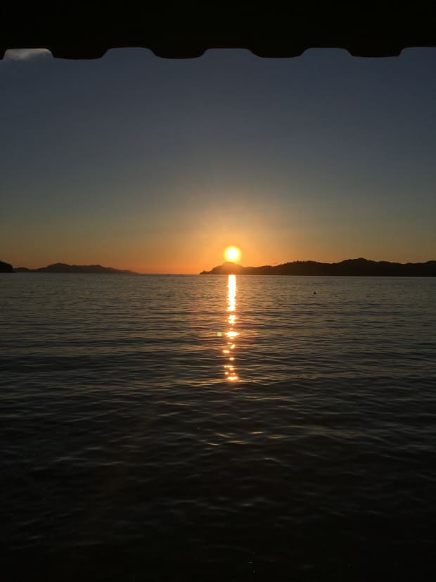 The sun setting behind an island landscape