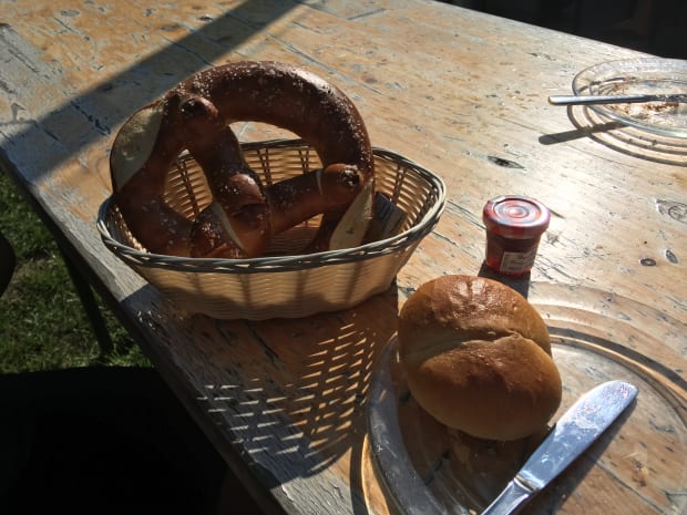 A bretzel in a bread basket, with jam.