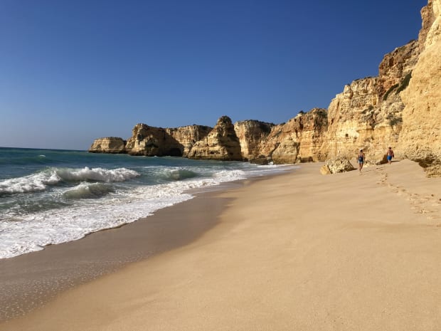 Looking over Praia de marinha beach, the waves crashing on one side and tall cliffs on the other.