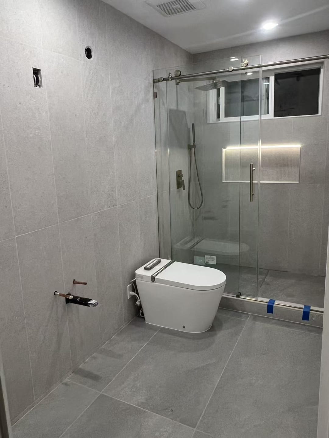 Glass shower next to stacked laundry