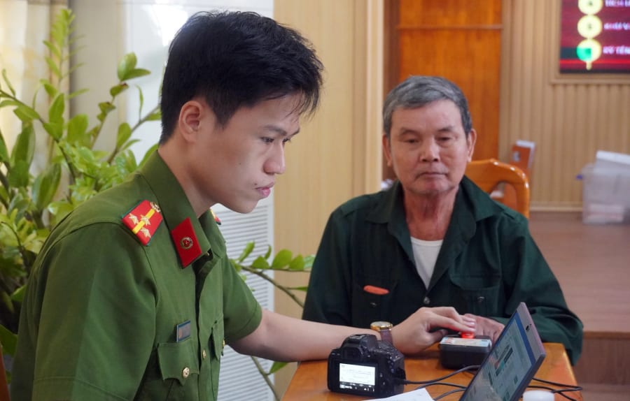 Cán bộ Công an hỗ trợ, hướng dẫn thân nhân liệt sĩ thực hiện quy trình lấy mẫu AND - Ảnh: N.M