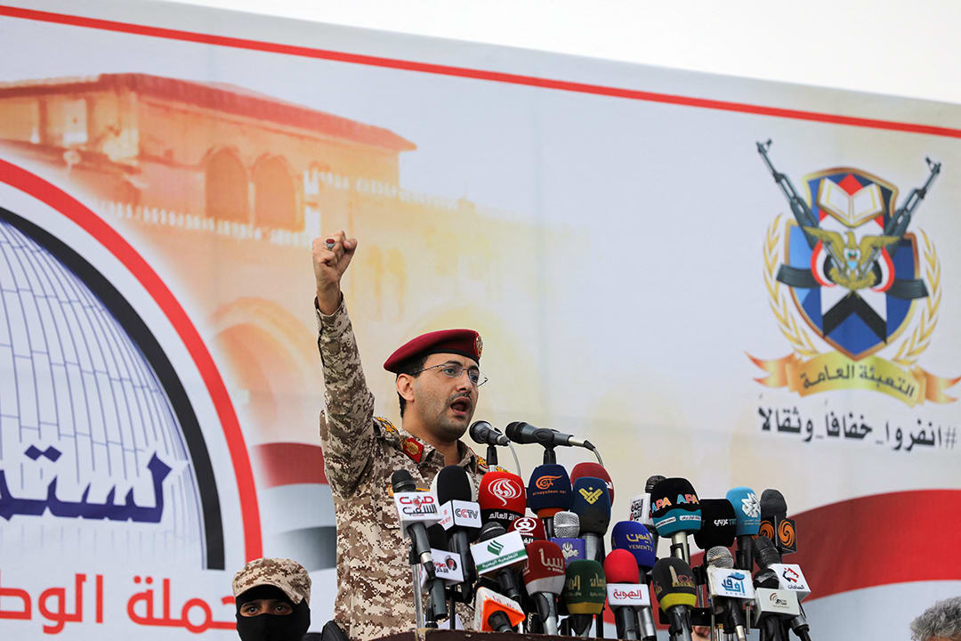 A man wearing military fatigues and a red beret pumps his first in the air while standing at a podium.