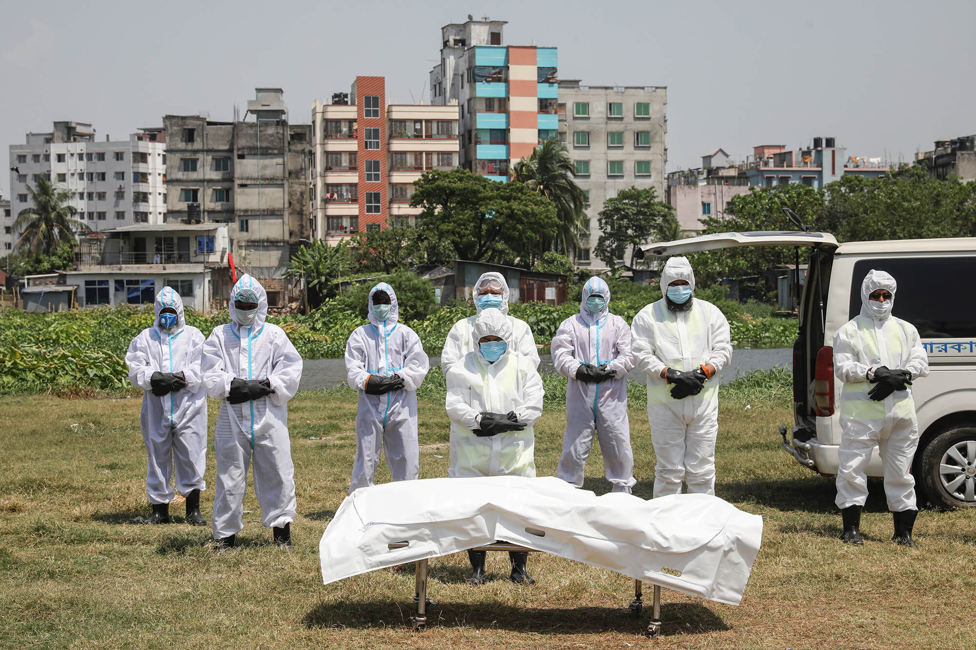 A group of people in masks and protective suits at a funeral.