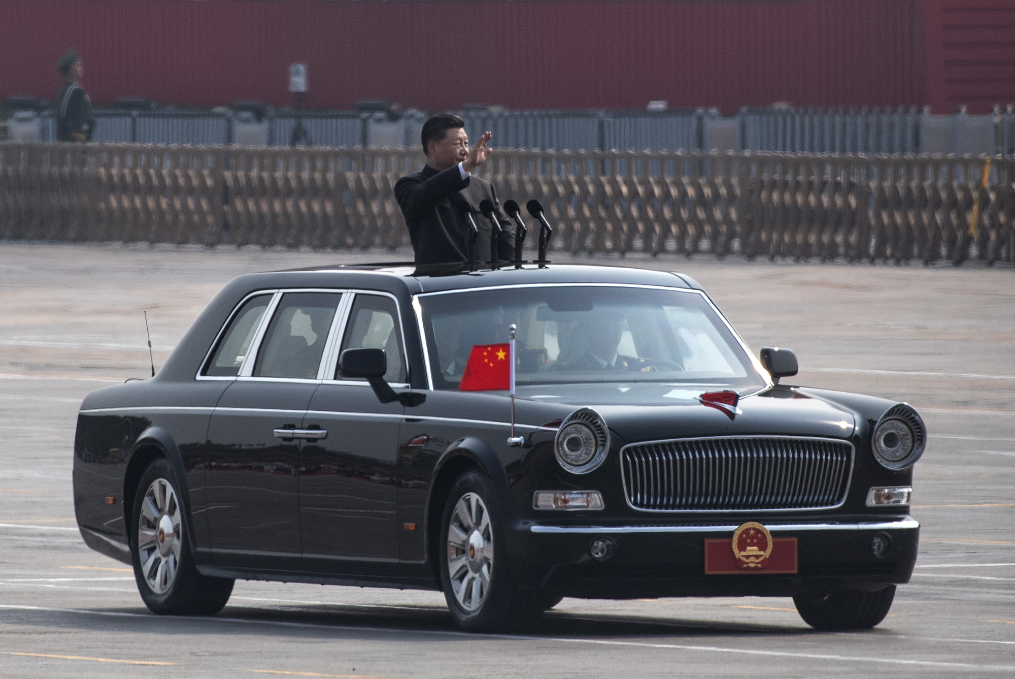 President Xi Jinping waves from his car as he drives after inspecting the troops during a parade.