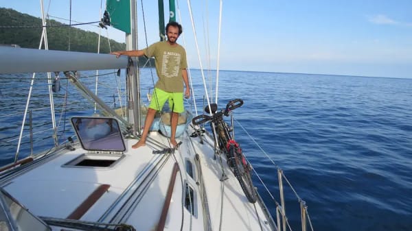 Viajero en velero y su bicicleta de bambu a un lado en la cubierta del velero