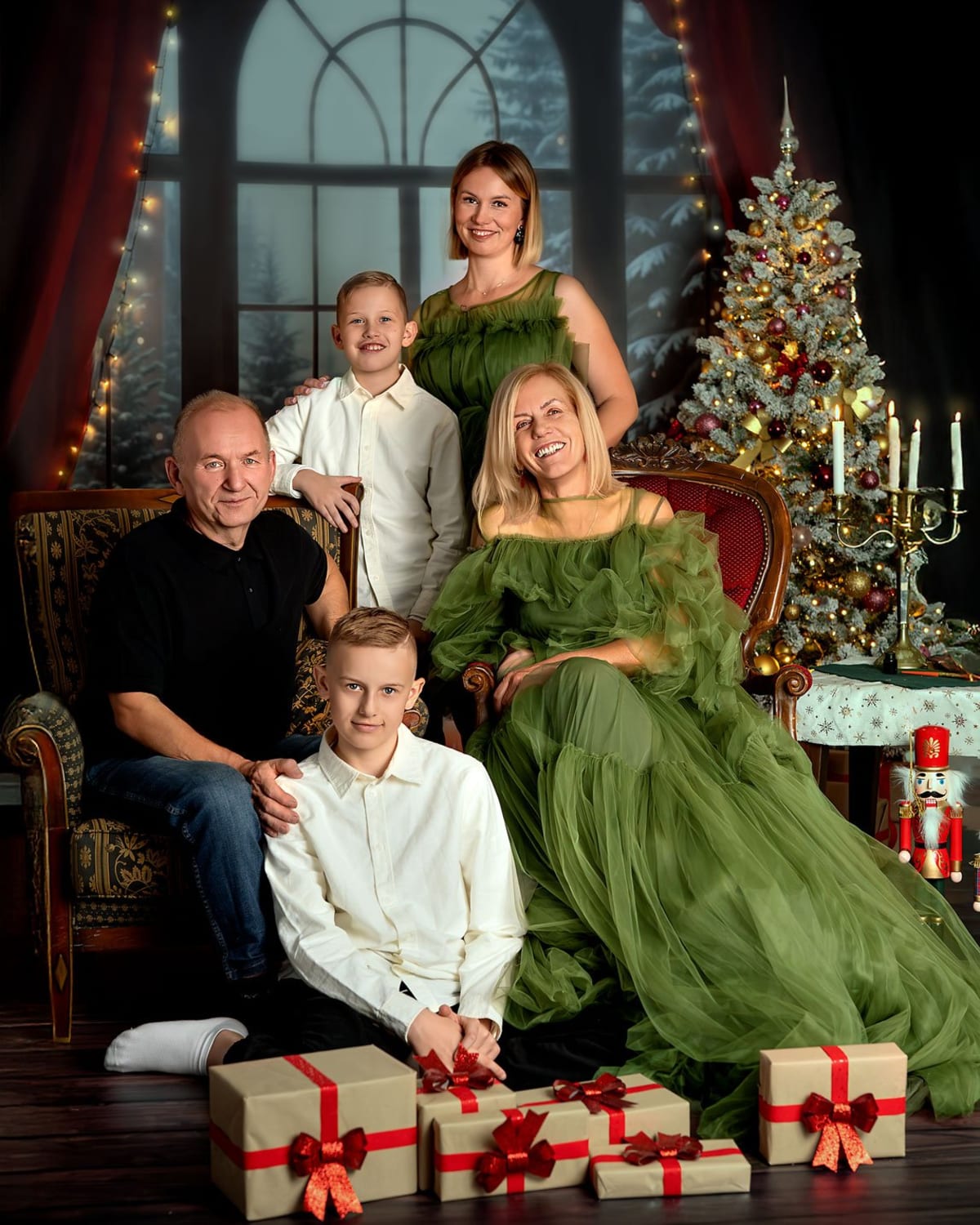 Rodzina czteroosobowa w eleganckich strojach pozuje do świątecznej sesji rodzinnej wśród dekoracji.