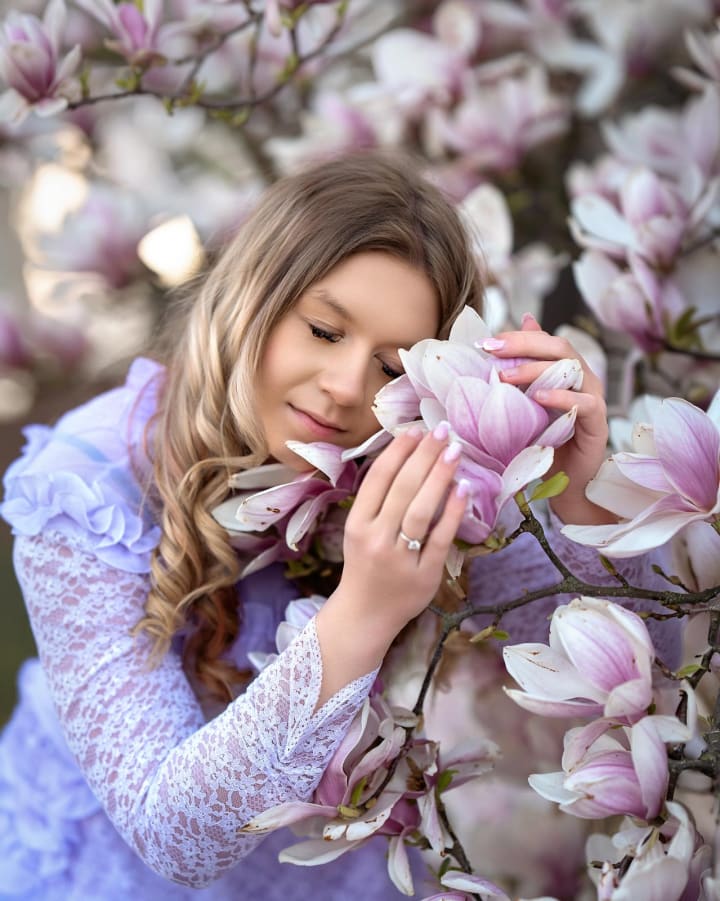Dziewczyna wśród kwitnących magnolii, sesja plenerowa wiosennych portretów w miękkim świetle.