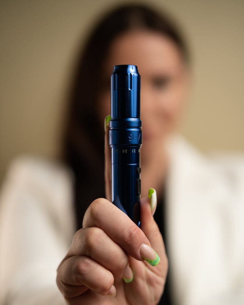 Dziewczyna w białej koszuli trzyma niebieski długopis, zielony manicure, zbliżenie na ręce, naturalne oświetlenie.