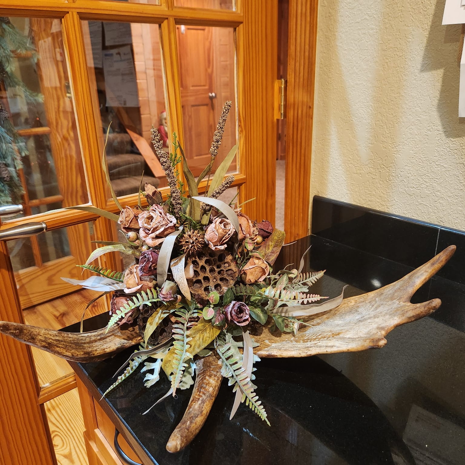 Antlers with pink flowers, ferns, and a honeycomb in the middle