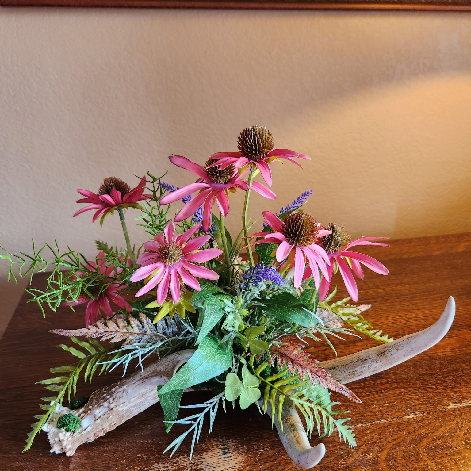 Deer antler with pink flowers, burrs, and ferns