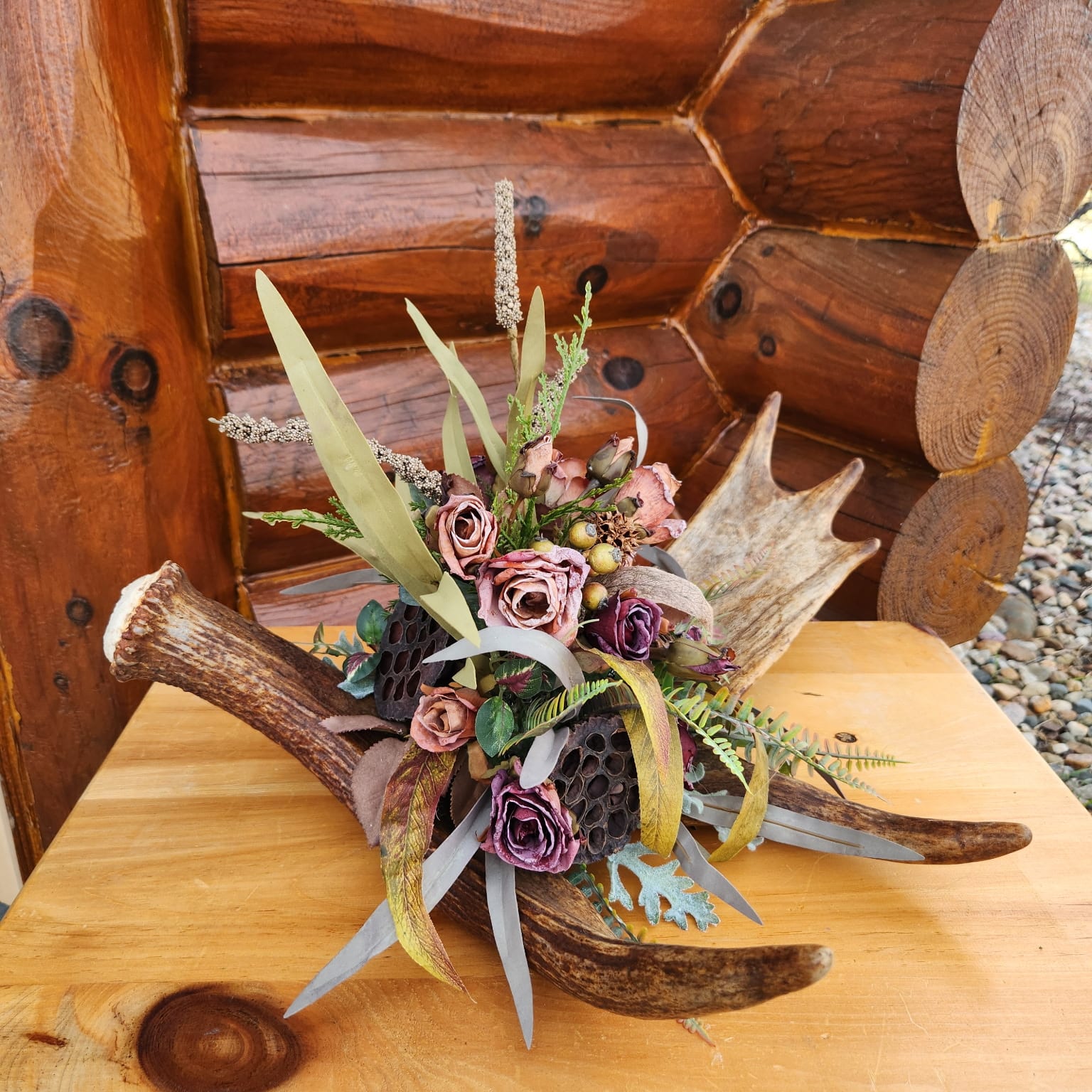 Deer antler with pink flowers, ferns, and a honeycomb in the middle