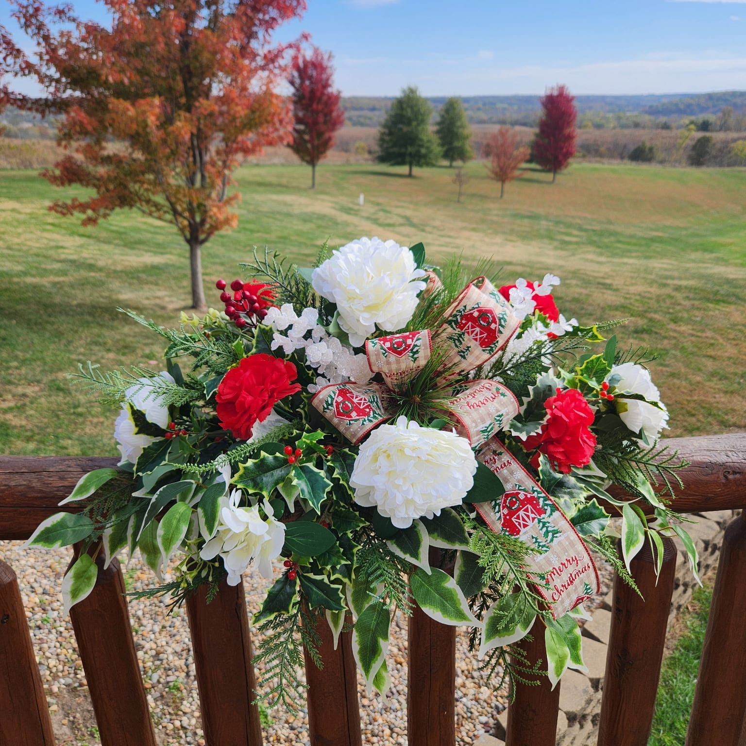 Red and white flowers with Christmas themed ribbon that has a barn on it and says Merry Christmas