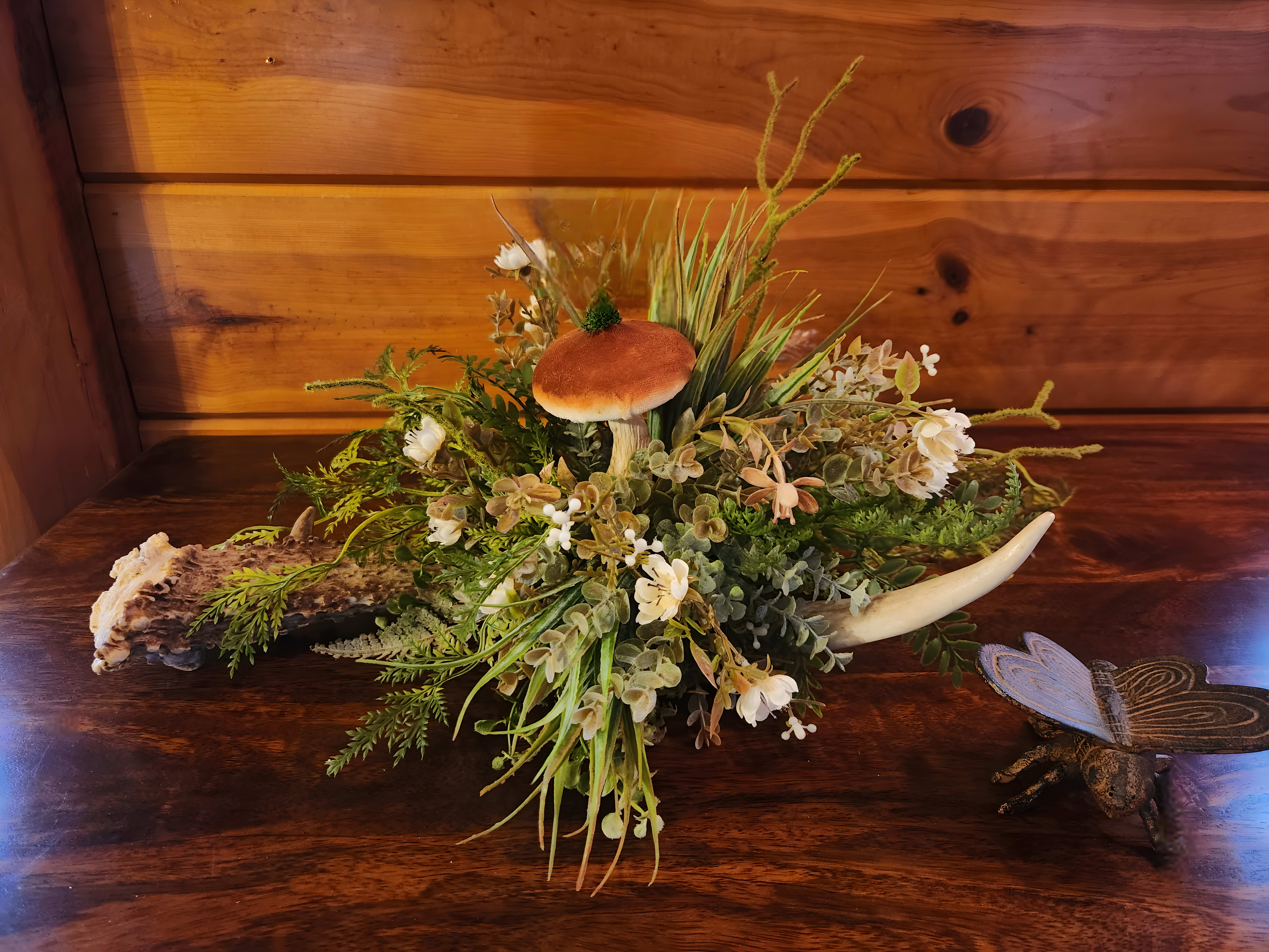 Forest arrangement with a mushroom in the middle and a small bug statue to the right