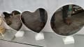 Front view: display of three tabletop mirrors (two heart-shaped with white frames and one round) on a glass shelf; white pedestal bases visible